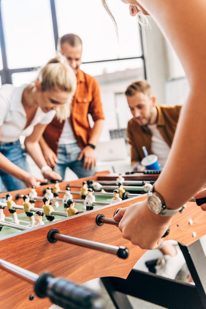cropped shot of young casual business people playing table football at office and having fun